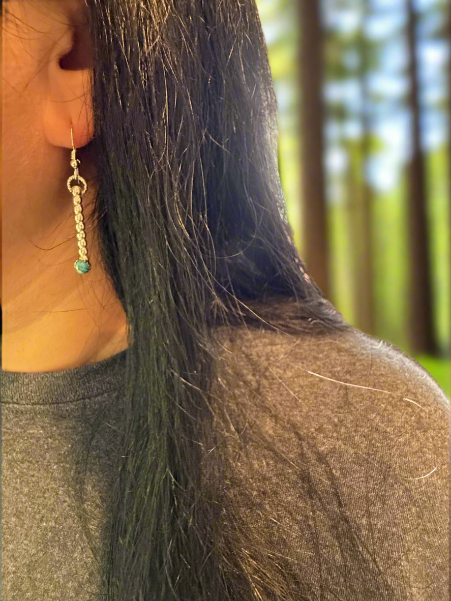 Close-up of a person wearing a turquoise earring with a blurred background